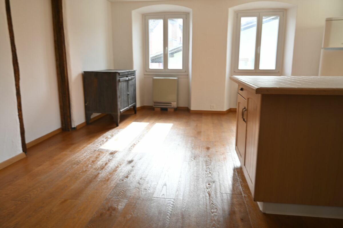 Heller Wohnraum mit Holzboden und zwei Fenstern