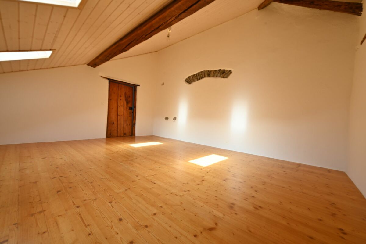 Dachgeschossraum mit Holzboden und sichtbaren Balken