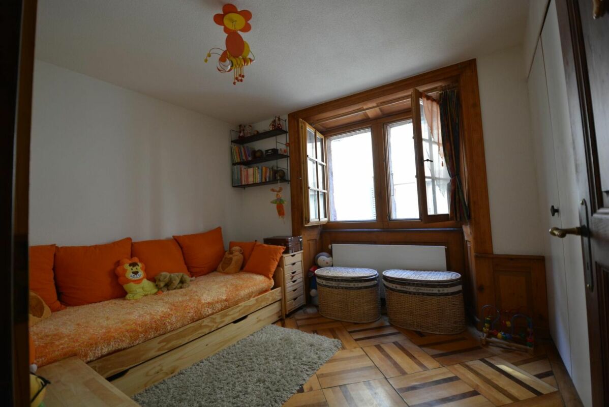 Kinderzimmer mit Holzfenster und orangefarbener Sitzgelegenheit