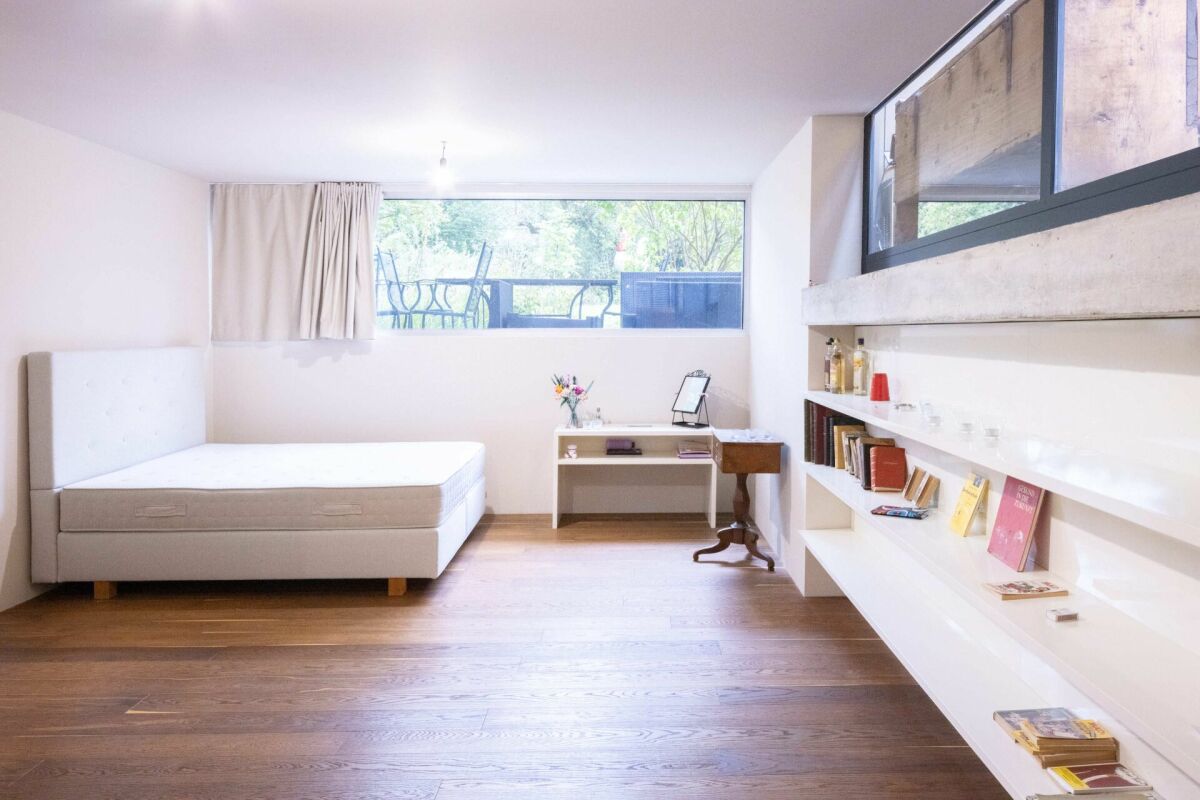 Helles, minimalistisch eingerichtetes Schlafzimmer mit großem Fenster und Wandregalen