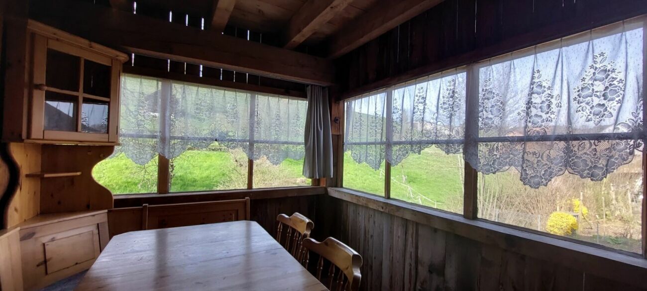 Rustikale Holzhütte mit großen Fenstern und Vorhängen