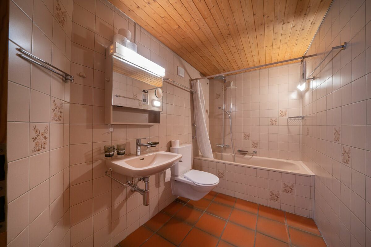 Badezimmer mit Badewanne und Holzdecke