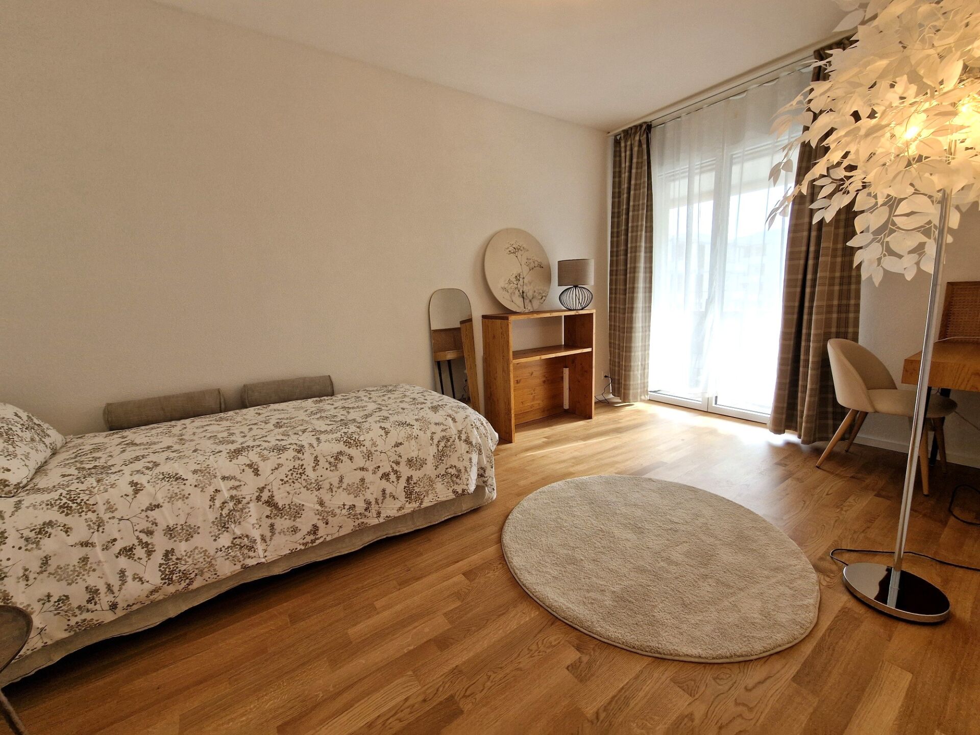 Helles Schlafzimmer mit Einzelbett und Fensterfront