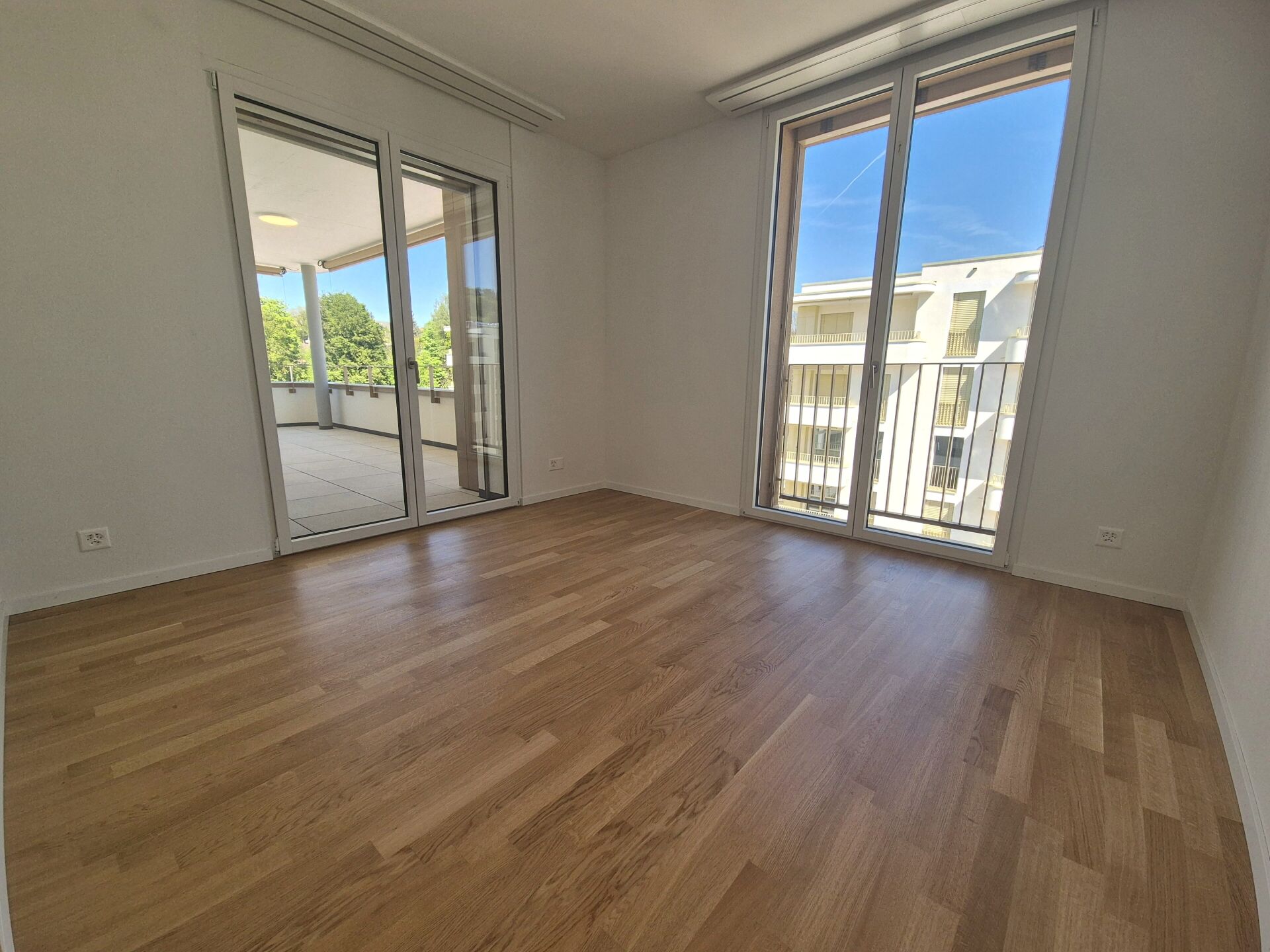 Leeres, helles Zimmer mit Balkonzugang