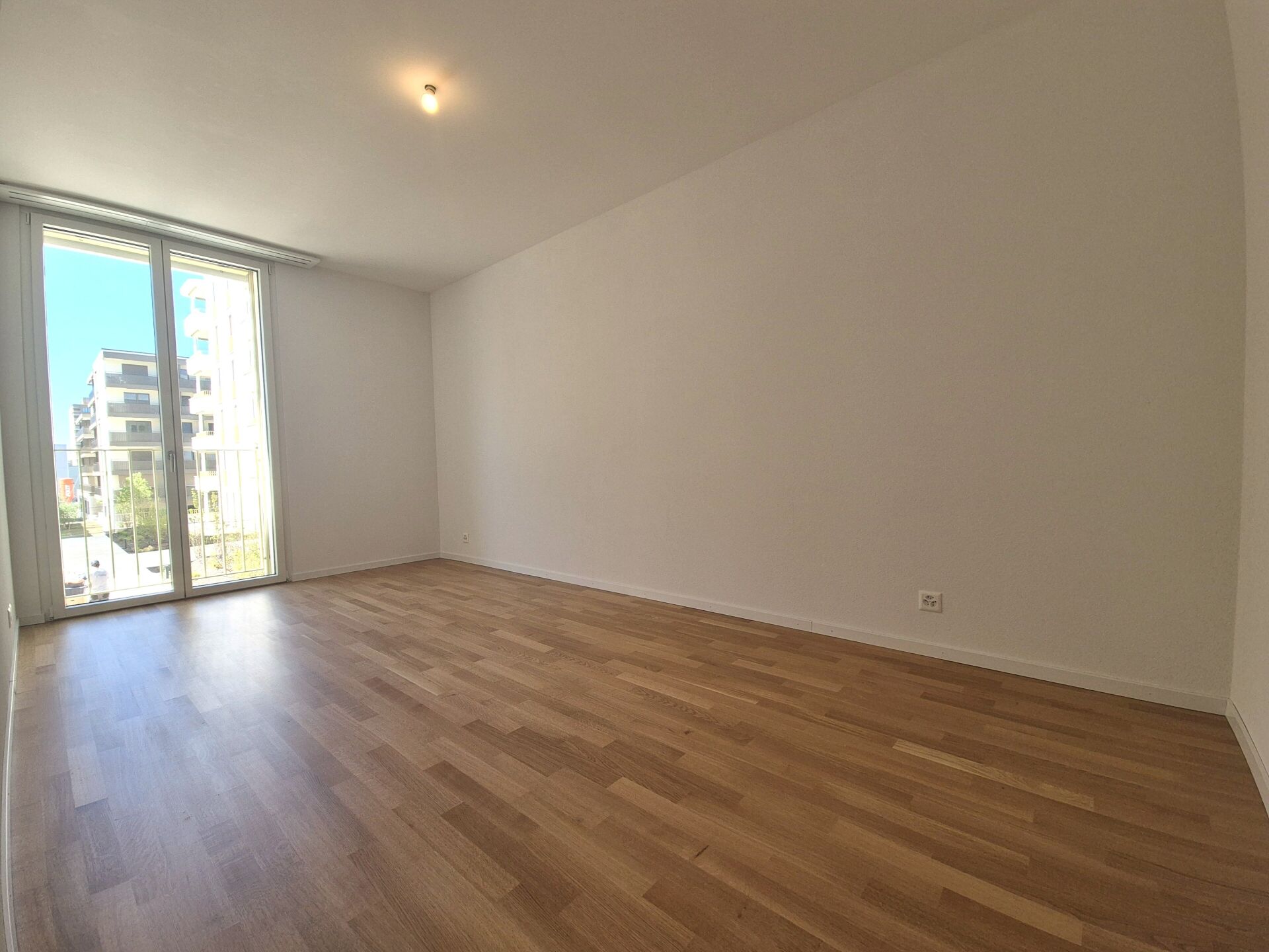 Heller leerer Raum mit Parkett und Balkonblick