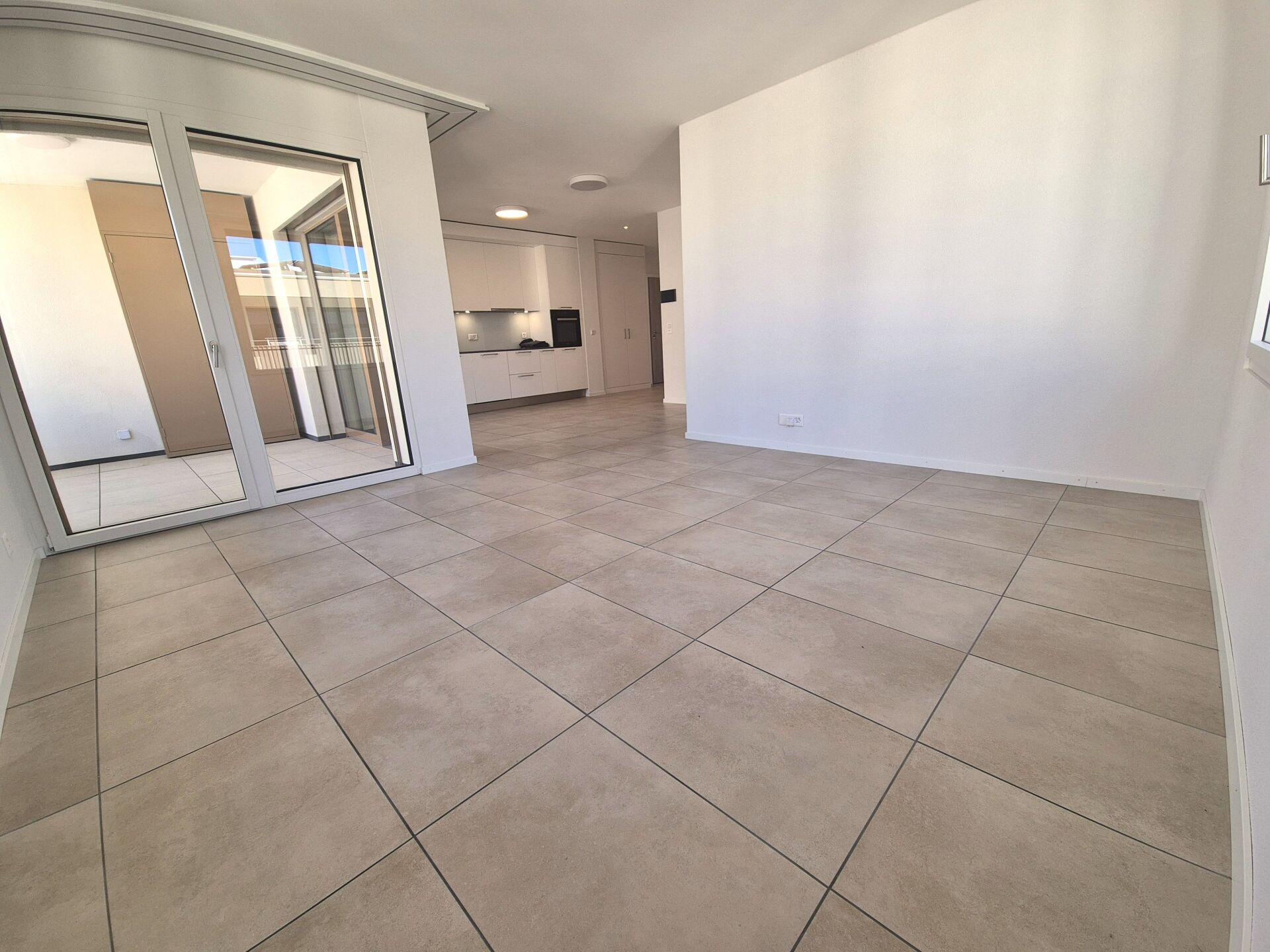Heller Wohnraum mit Fliesenboden und Zugang zum Balkon