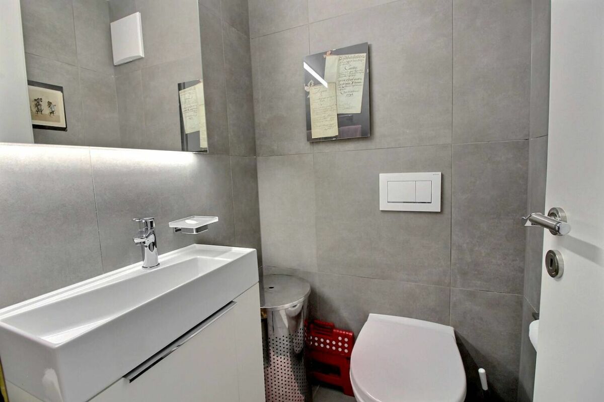 Modernes Gäste-WC mit grauen Fliesen und weißem Waschtisch