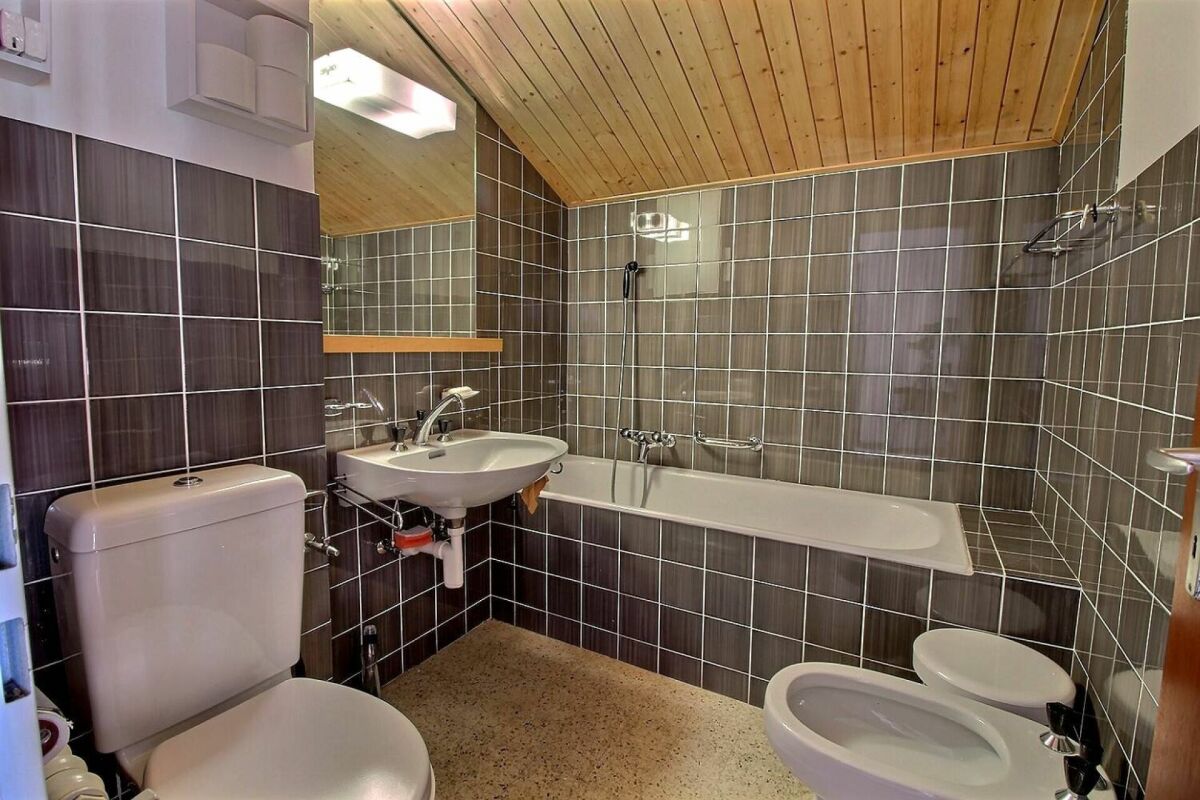 Badezimmer mit braunen Wandfliesen und Holzdecke