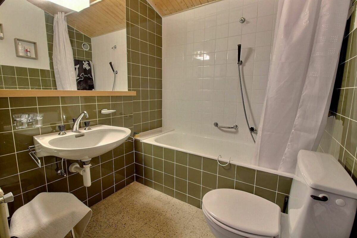 Badezimmer mit Badewanne und grün gefliesten Wänden