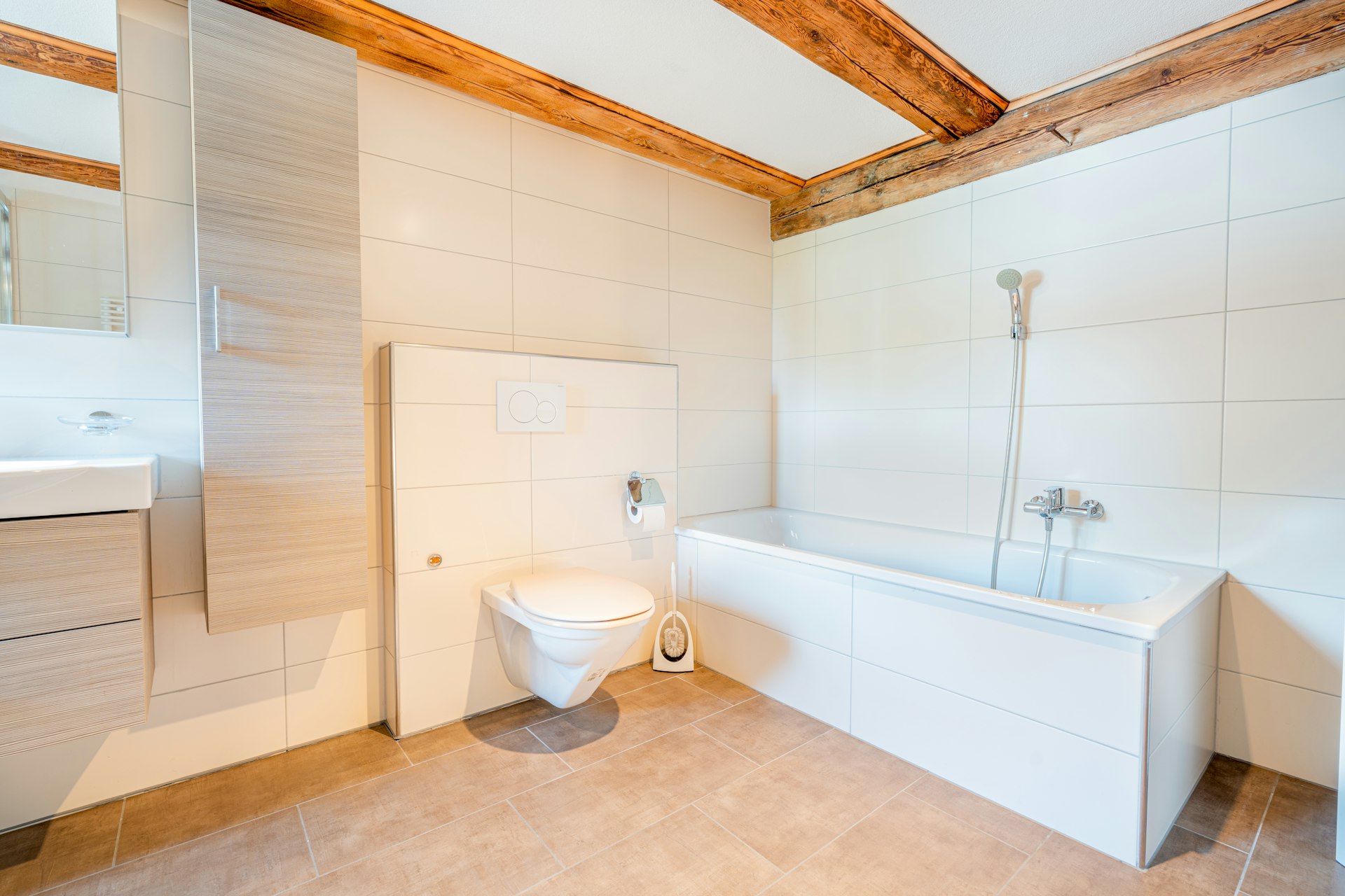 Helles Badezimmer mit Badewanne und sichtbaren Holzbalken