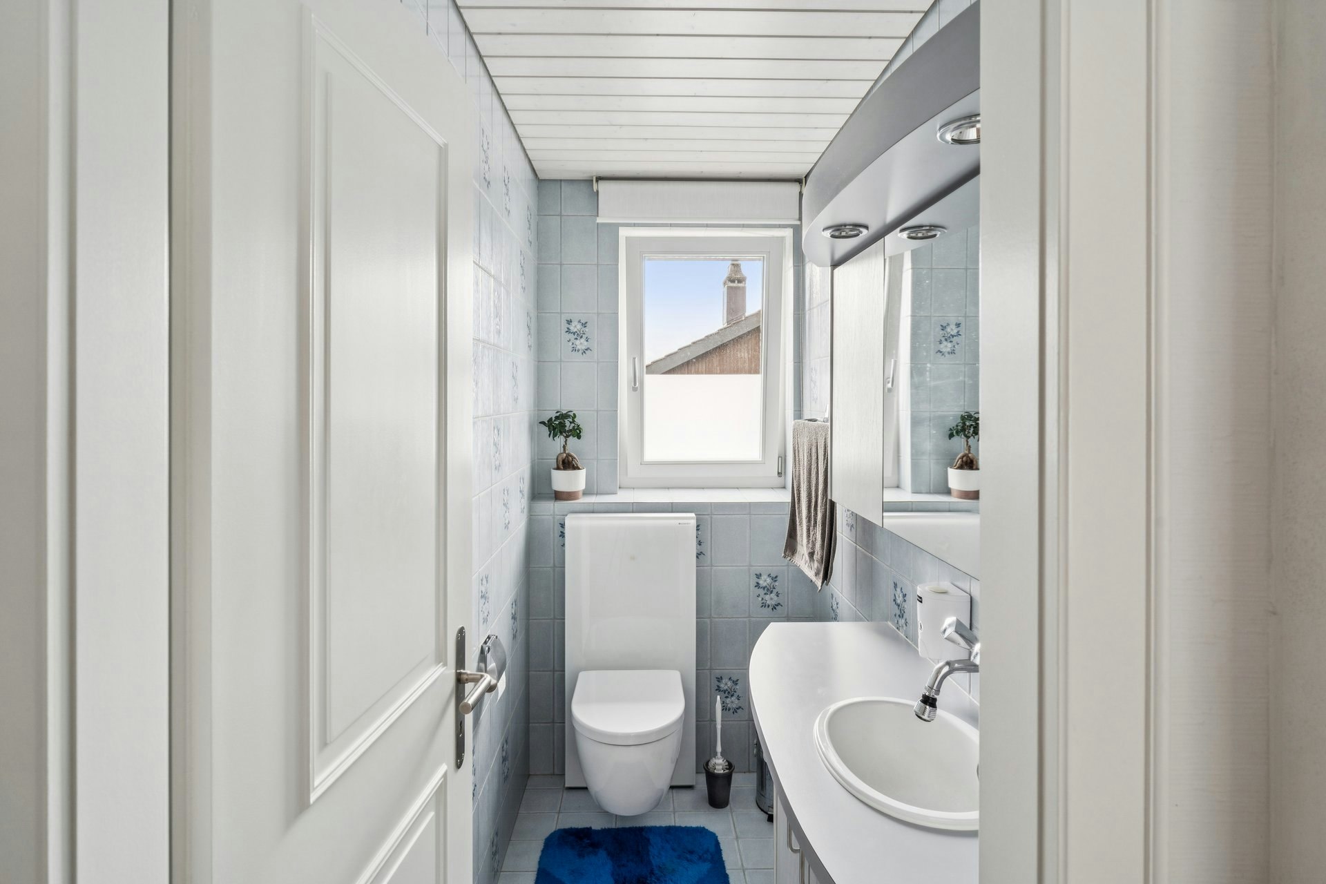 Kleines, helles Gäste-WC mit blau gefliesten Wänden und Dachfenster