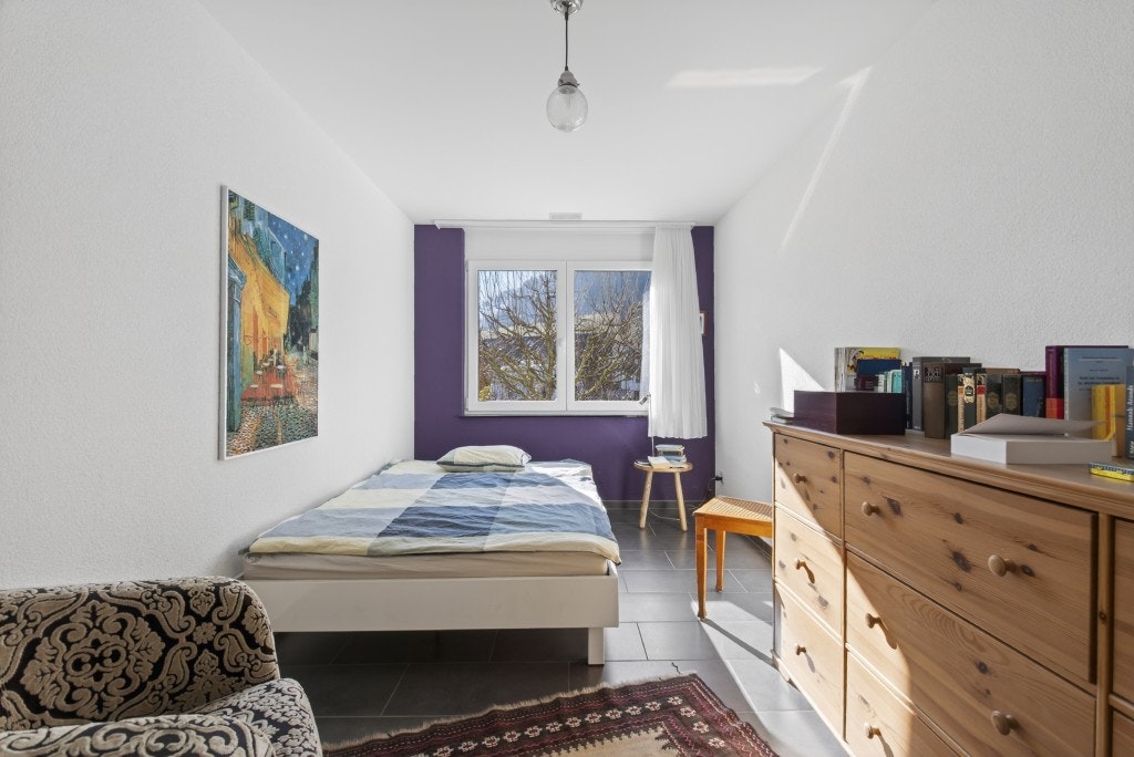 Schmales Schlafzimmer mit Fenster und Holzmöbeln