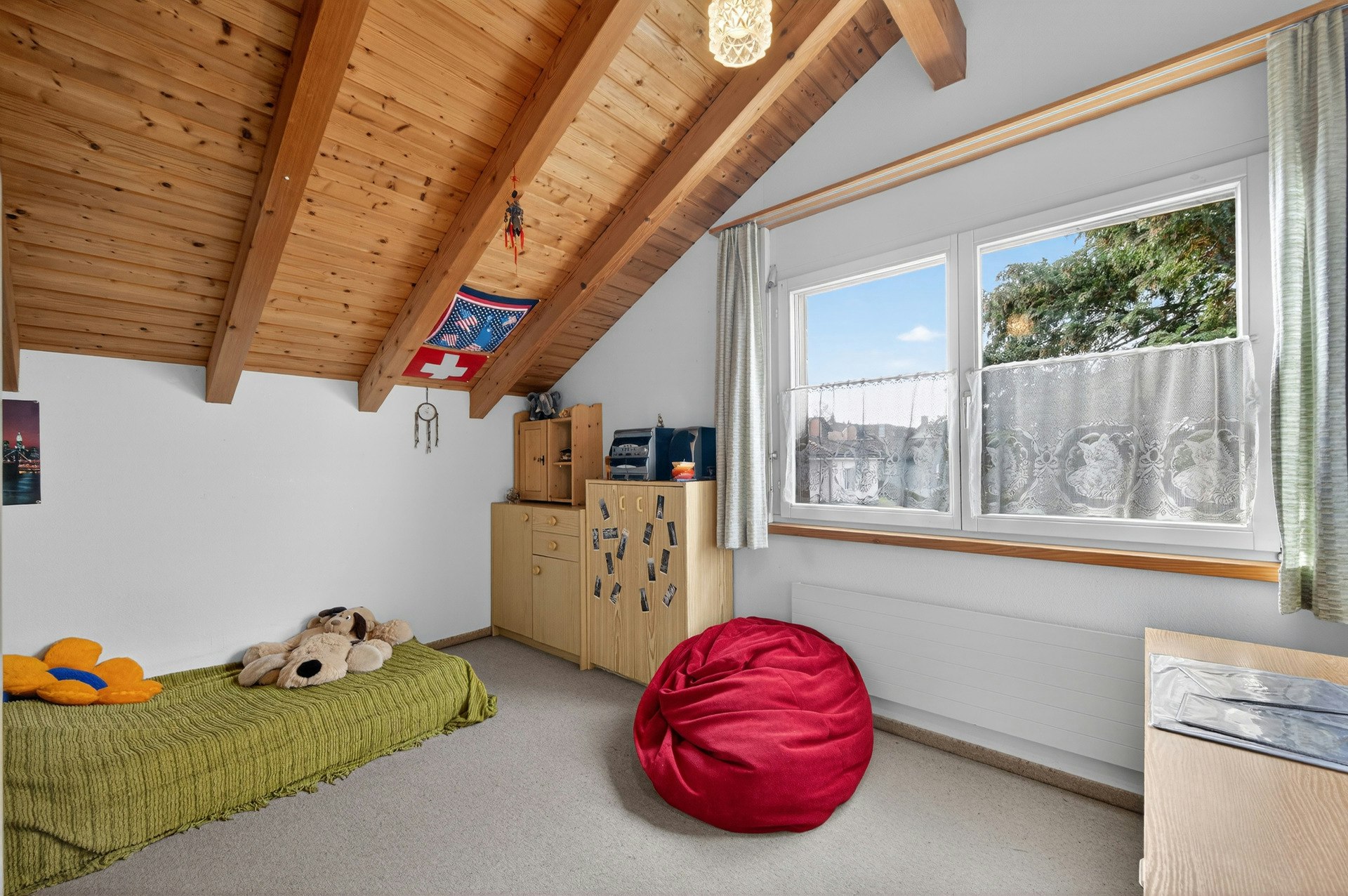 Dachgeschosszimmer mit Holzdecke und Fensterblick