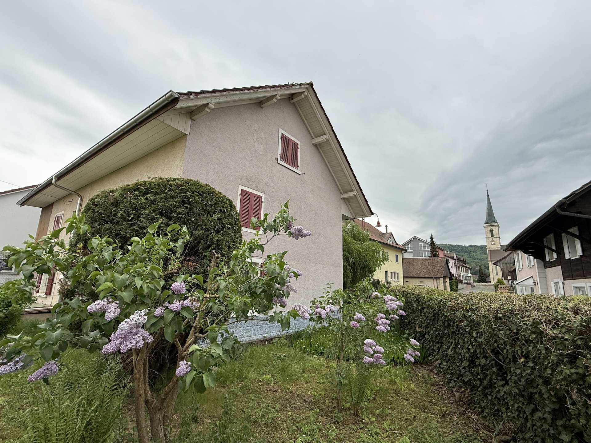 Wohnhaus mit Garten und Kirchturm im Hintergrund