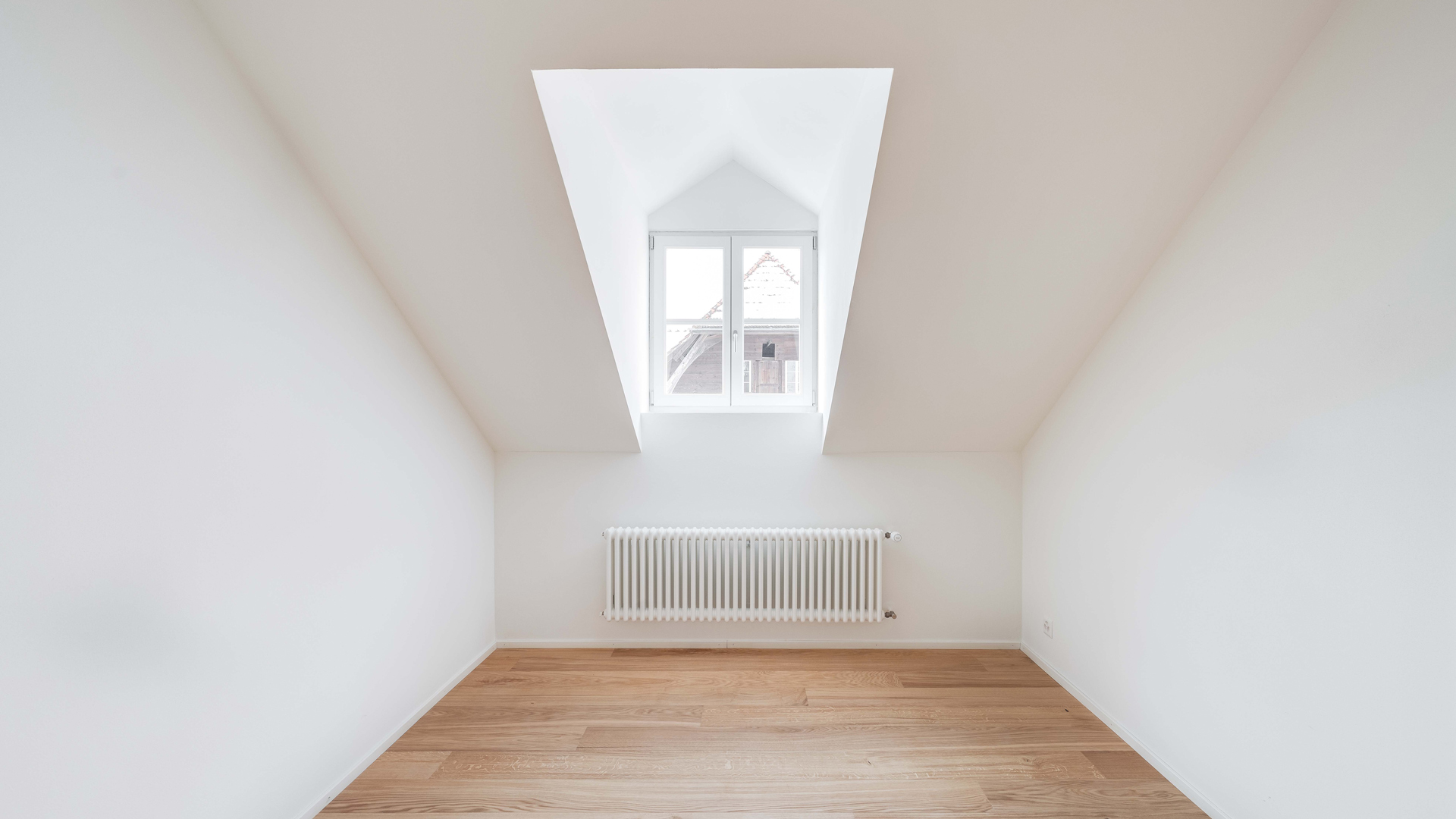 Heller Dachraum mit Fenster und Heizkörper