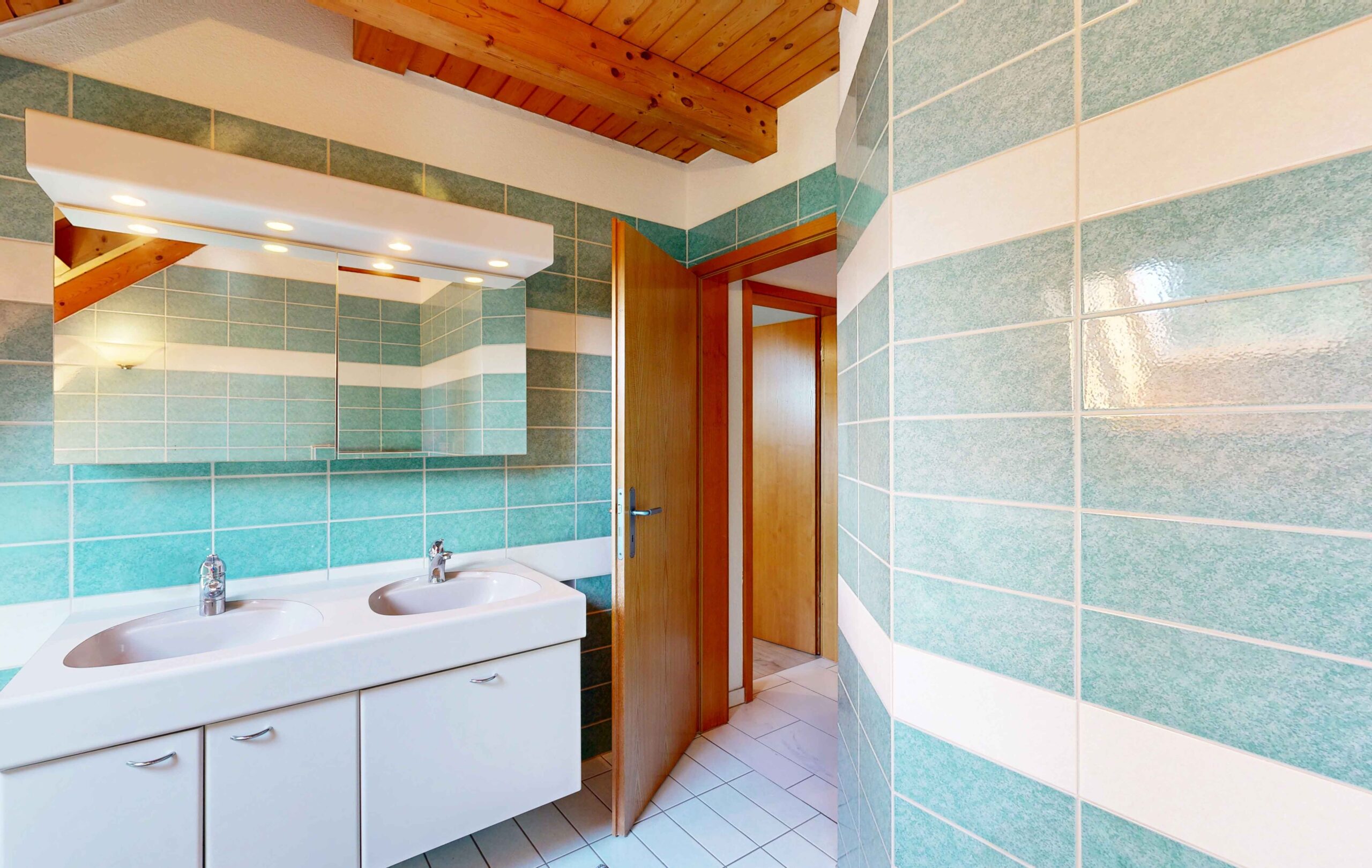Badezimmer mit türkisfarbenen Fliesen und Holzdecke