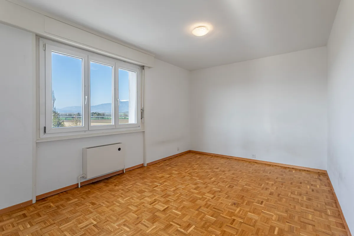 Heller leerer Raum mit Parkettboden und Fensterblick