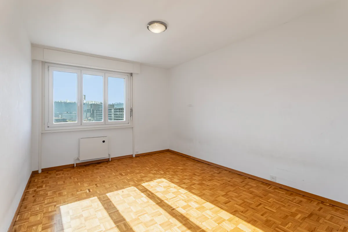 Heller leerer Wohnraum mit Parkett und Fensterblick