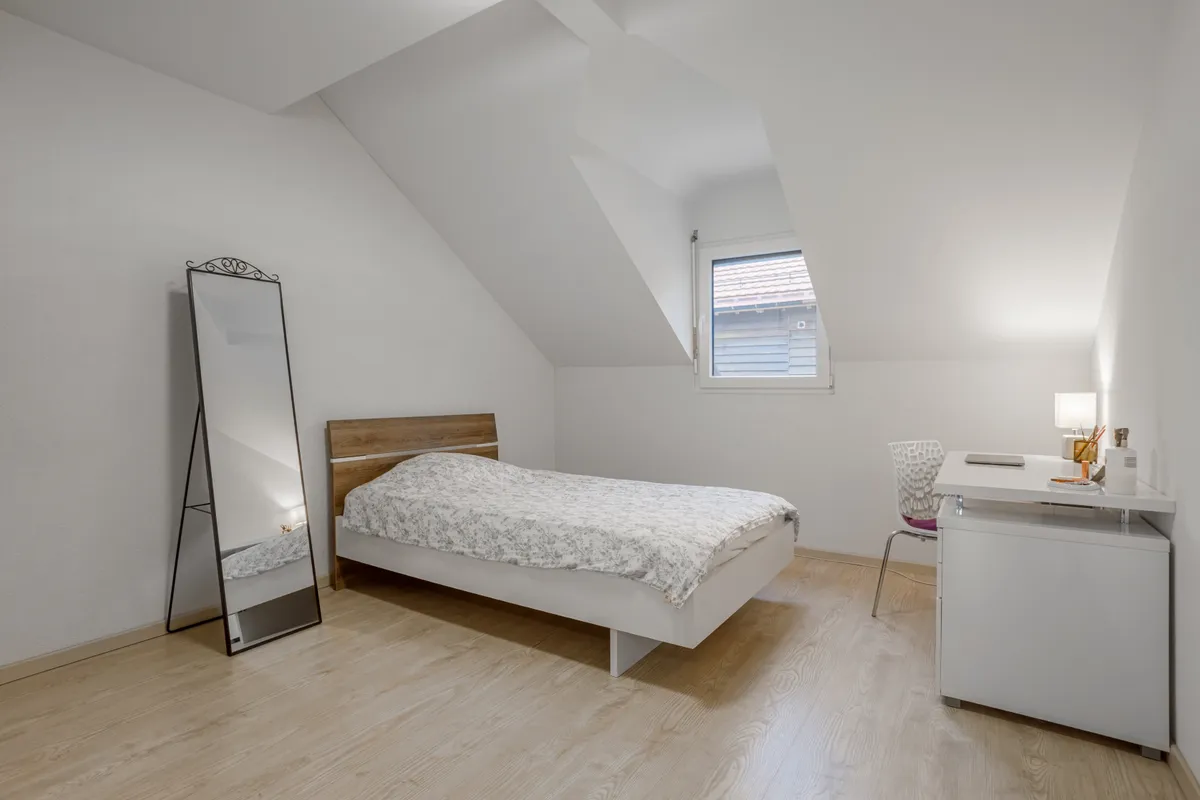 Dachgeschoss-Schlafzimmer mit Schreibtisch und Spiegel