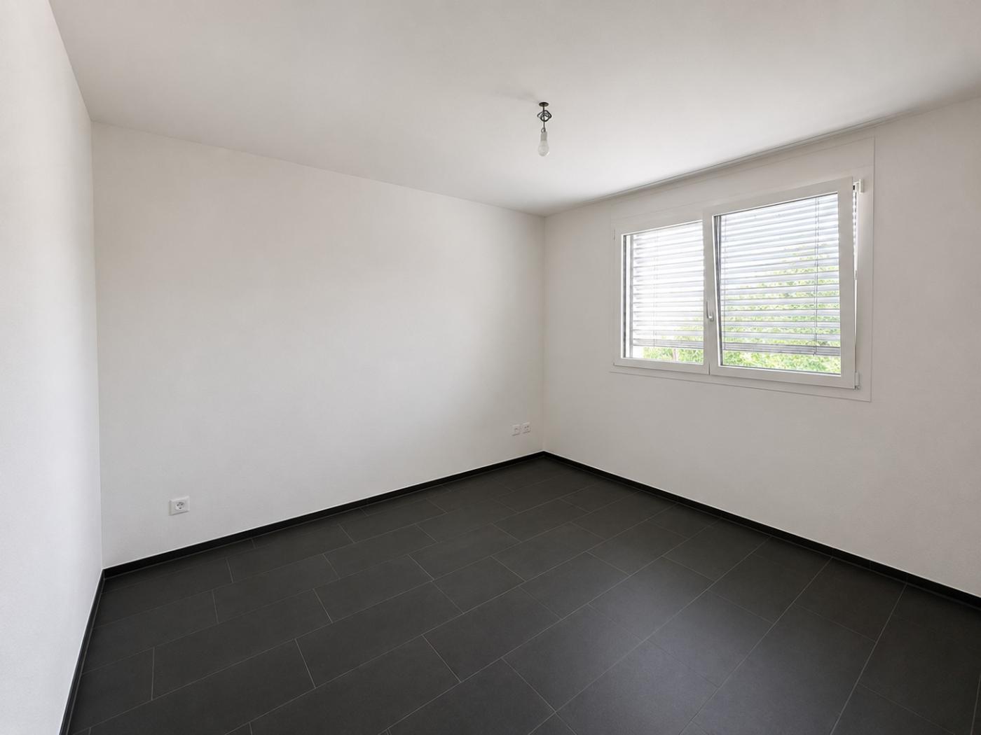 Leeres, modern wirkendes Zimmer mit Fliesenboden und Fenster