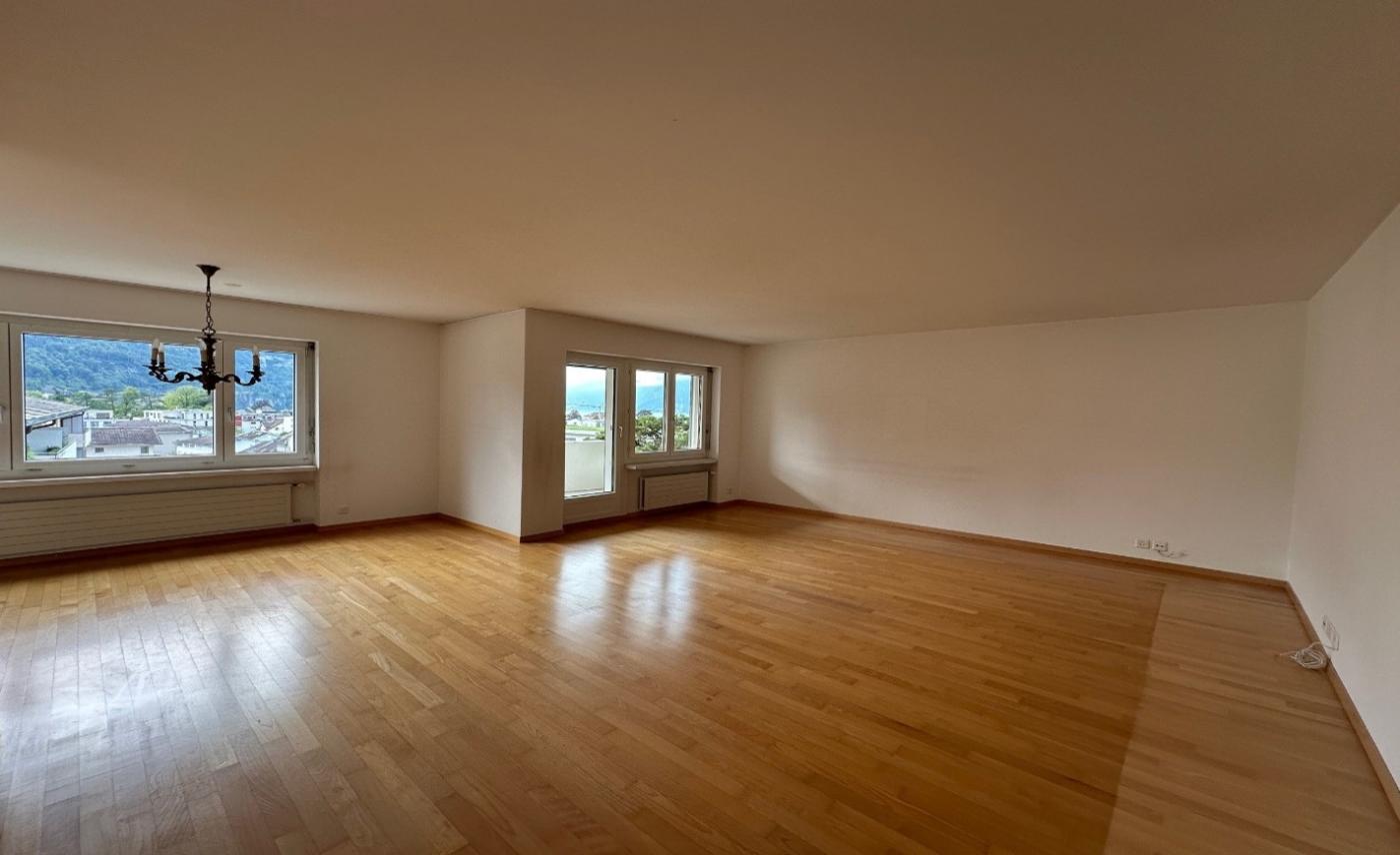 Großer leerer Wohnraum mit Parkett und Bergblick