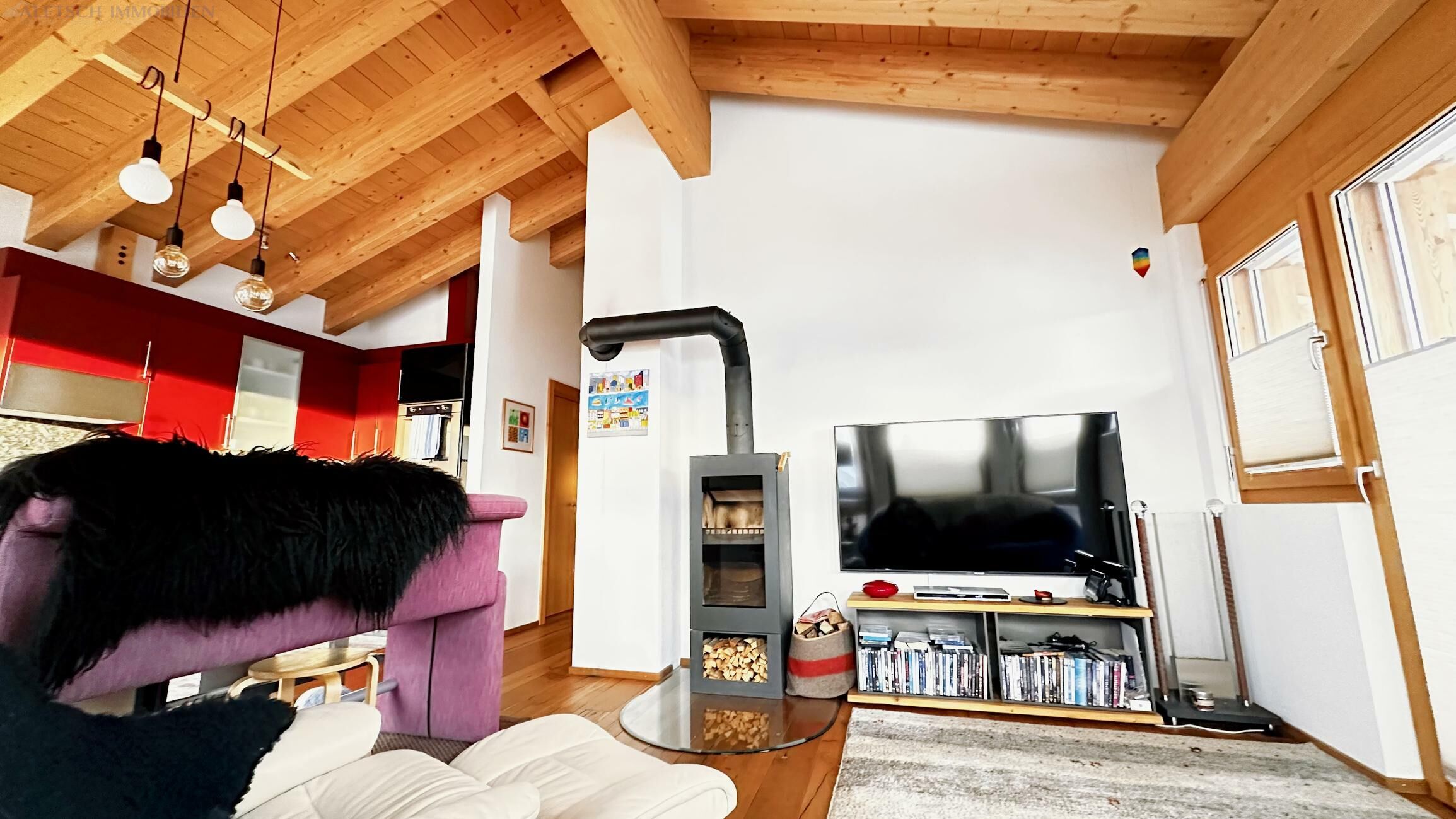 Gemütliches Wohnzimmer mit sichtbarer Holzdecke und Kaminofen