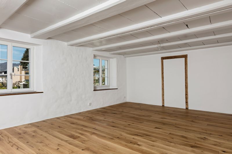 Heller leerer Raum mit Holzboden und sichtbaren Deckenbalken