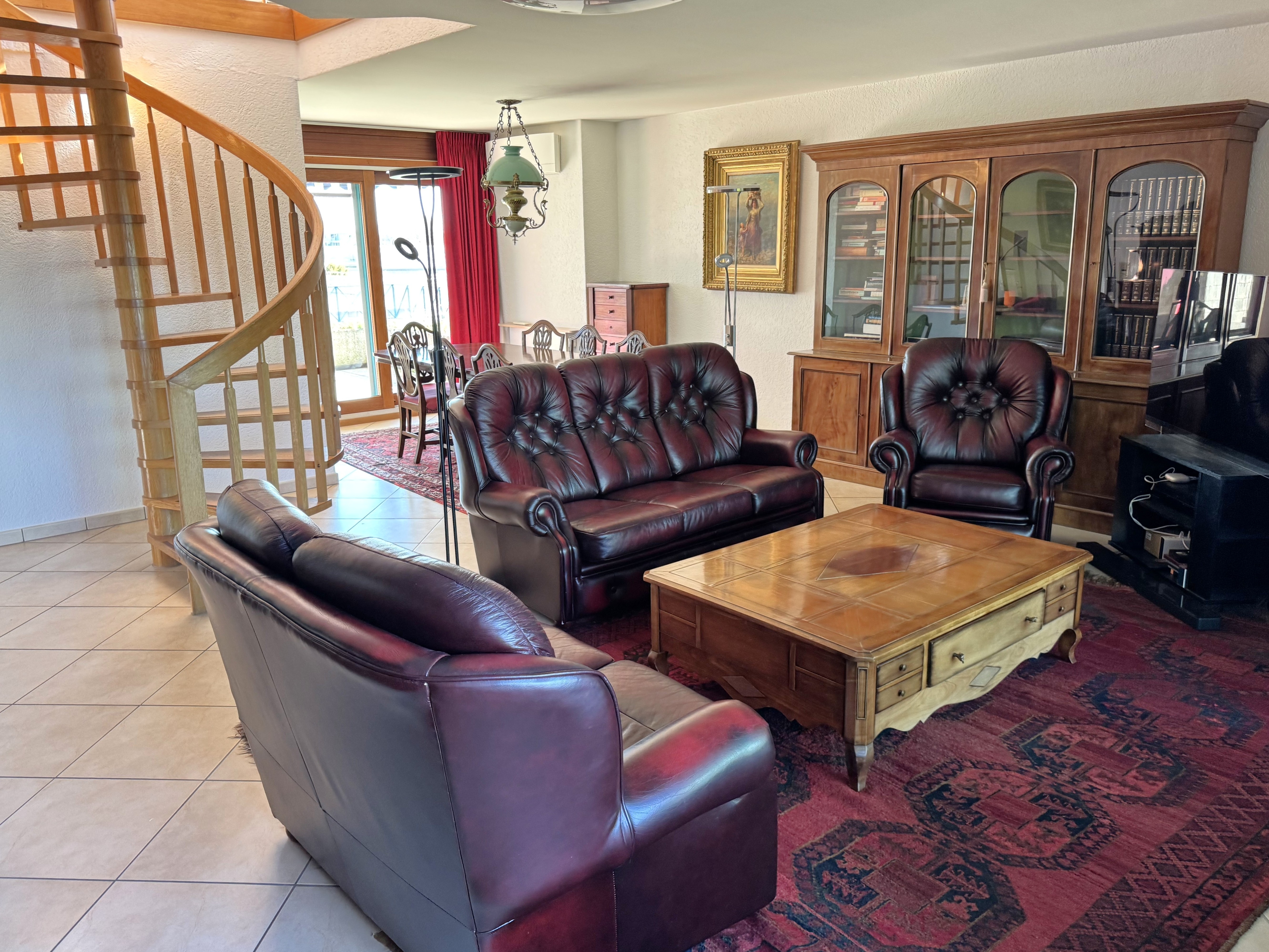 Wohnzimmer mit Holztreppe und klassischen Sitzmöbeln
