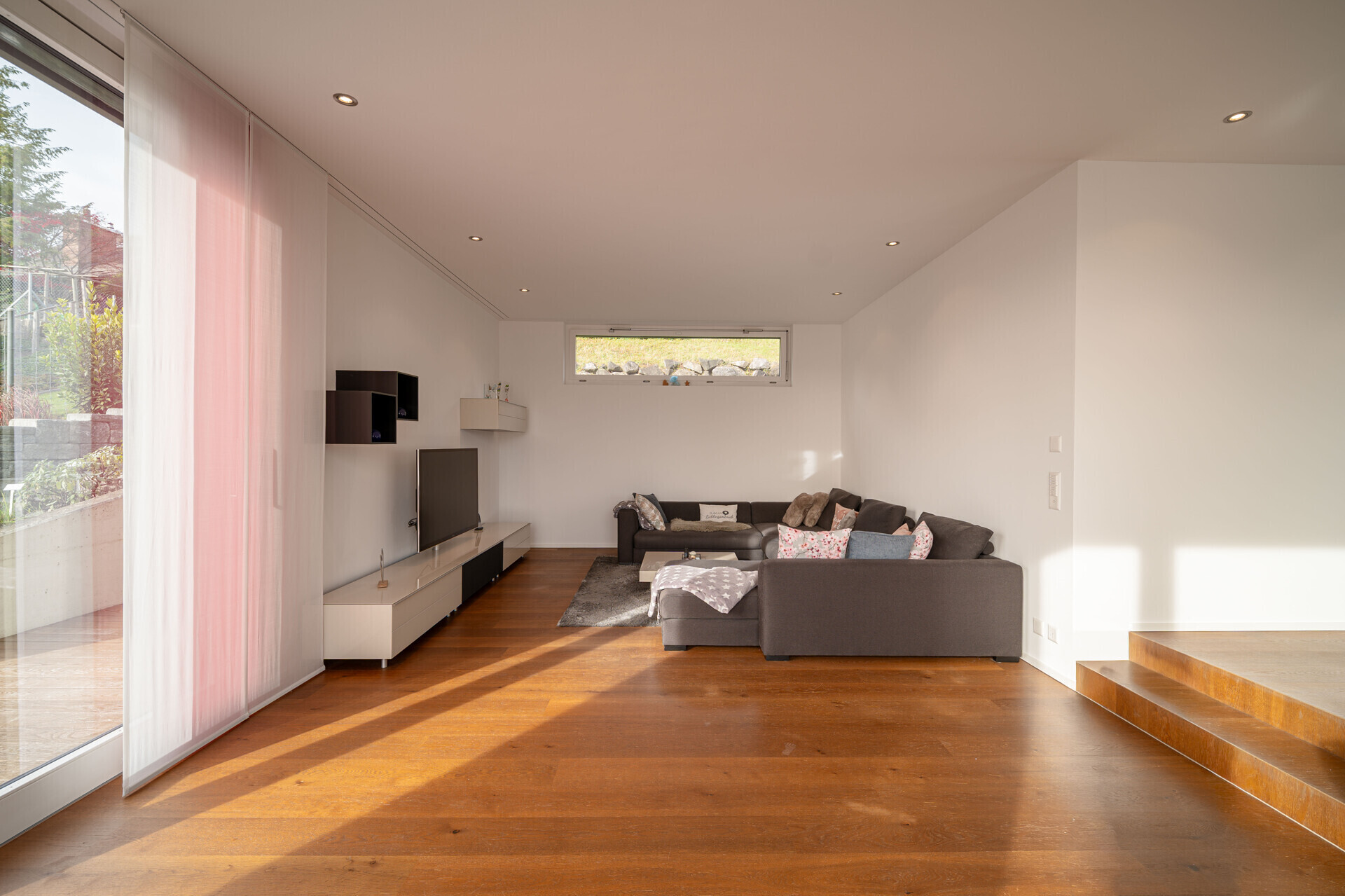 Heller Wohnraum mit Holzfußboden und großer Fensterfront