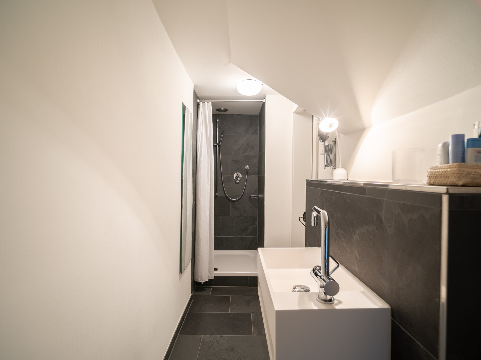 Schmales Badezimmer mit Dusche und Waschtisch