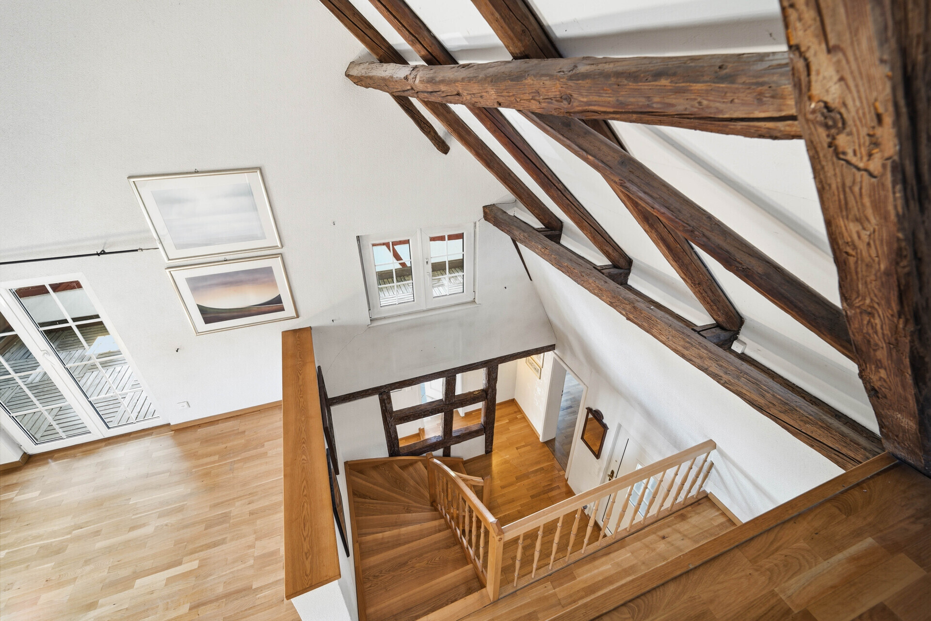 Luftiges Dachgeschoss mit sichtbaren Holzbalken und Treppe
