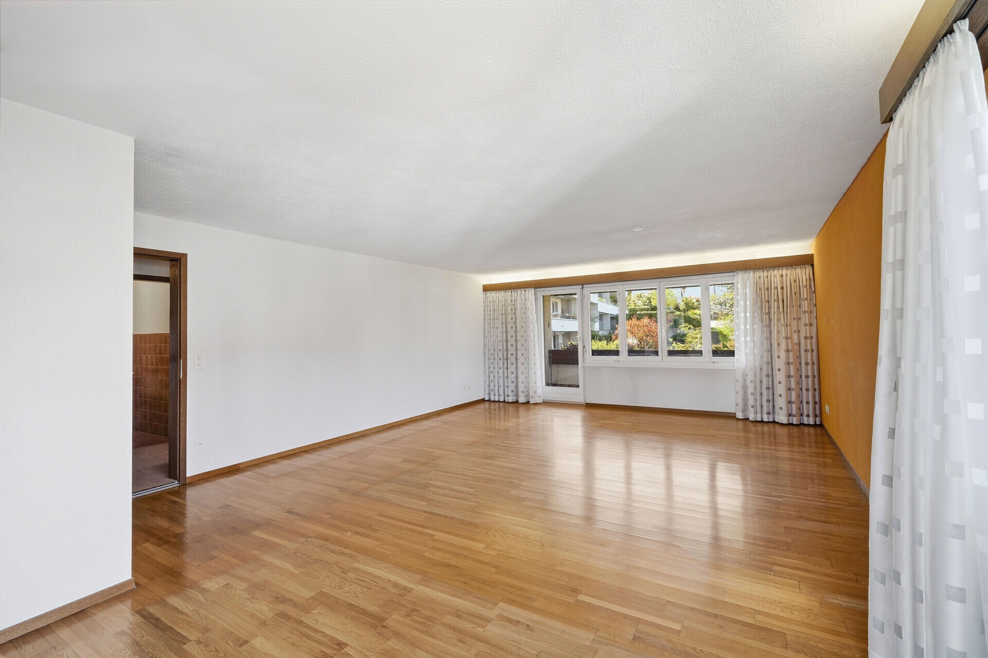 Helles leeres Wohnzimmer mit Holzparkett
