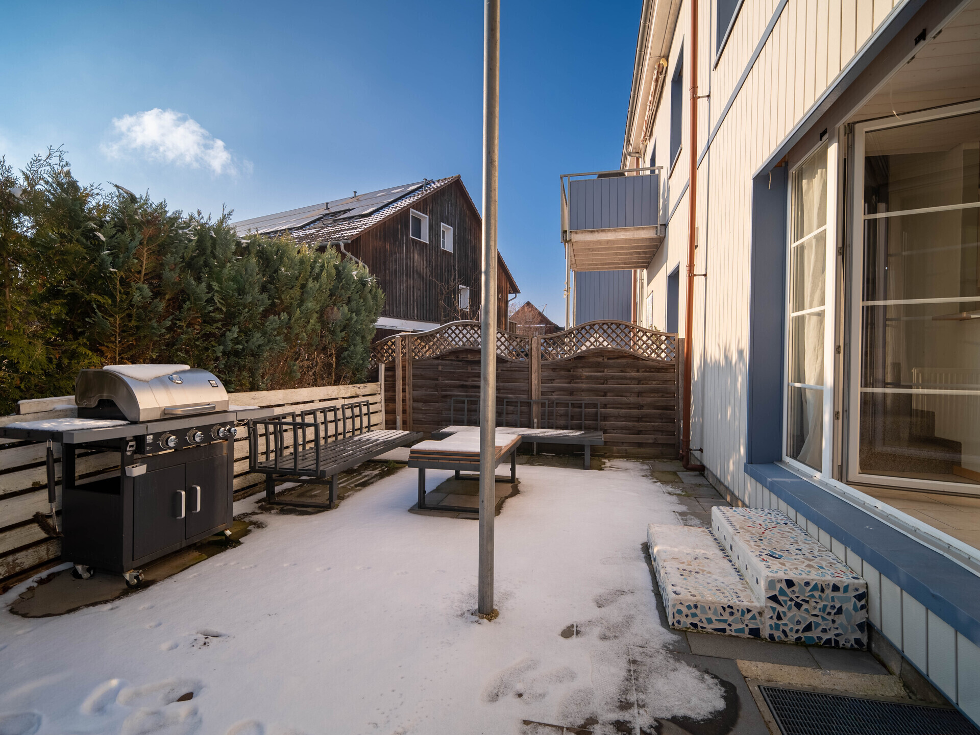 Schneebedeckter Außenhof mit Grill und Terrasse