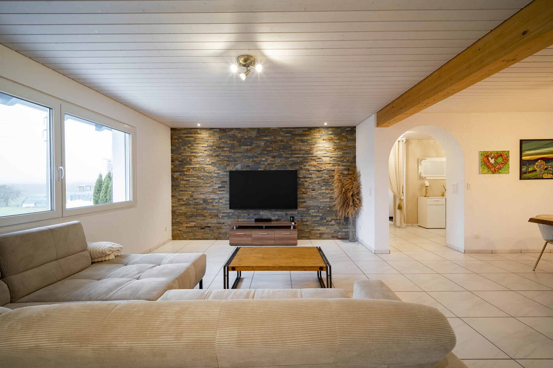 Heller Wohnraum mit Steinwand und TV
