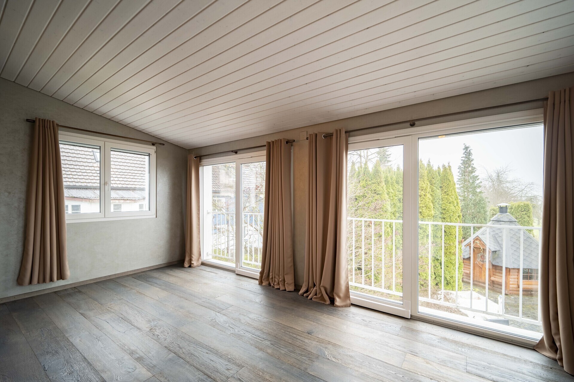 Heller leerer Wohnraum mit großen Fenstern und Balkonblick