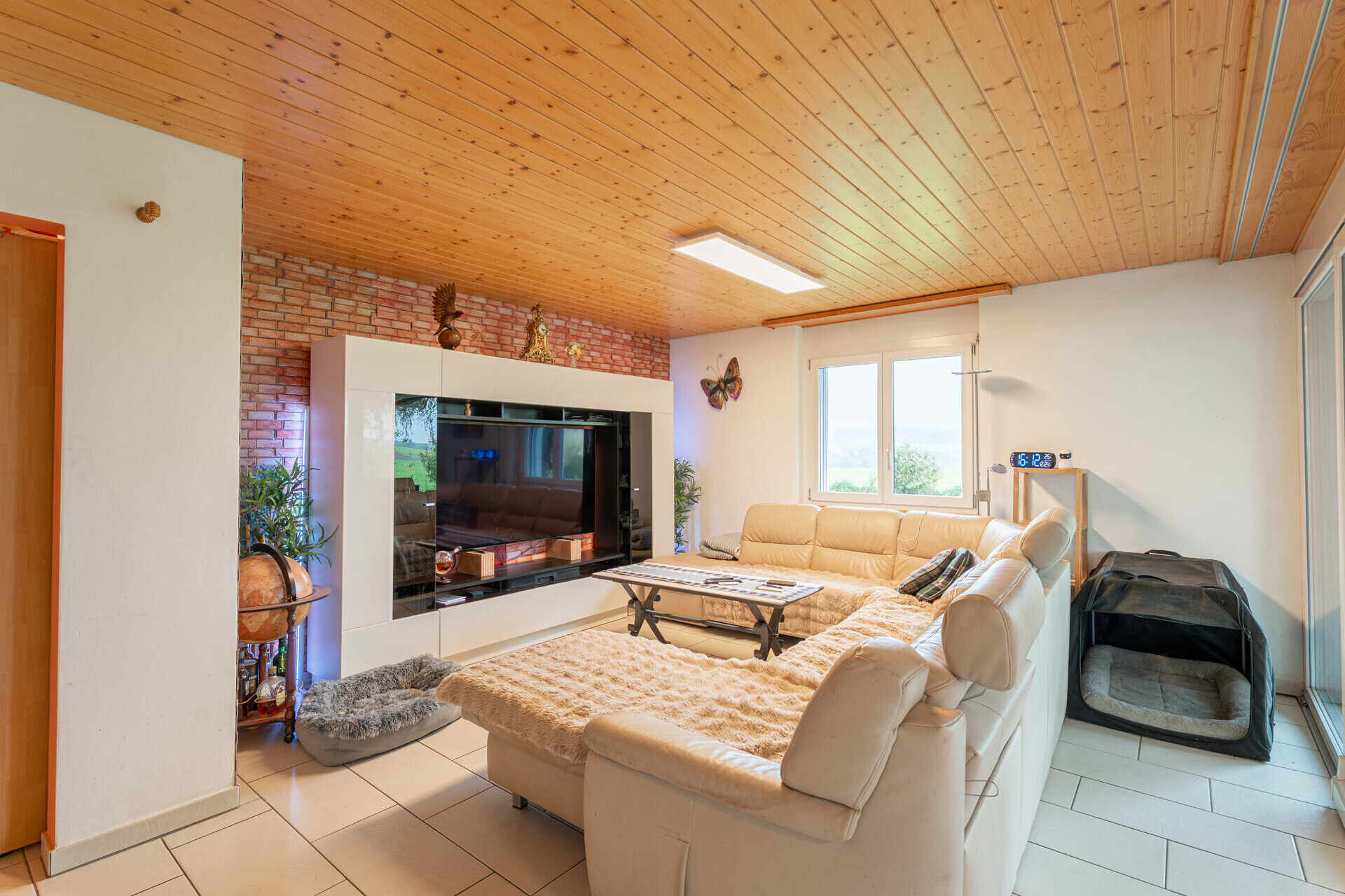 Wohnzimmer mit großer Sofalandschaft und TV-Wand