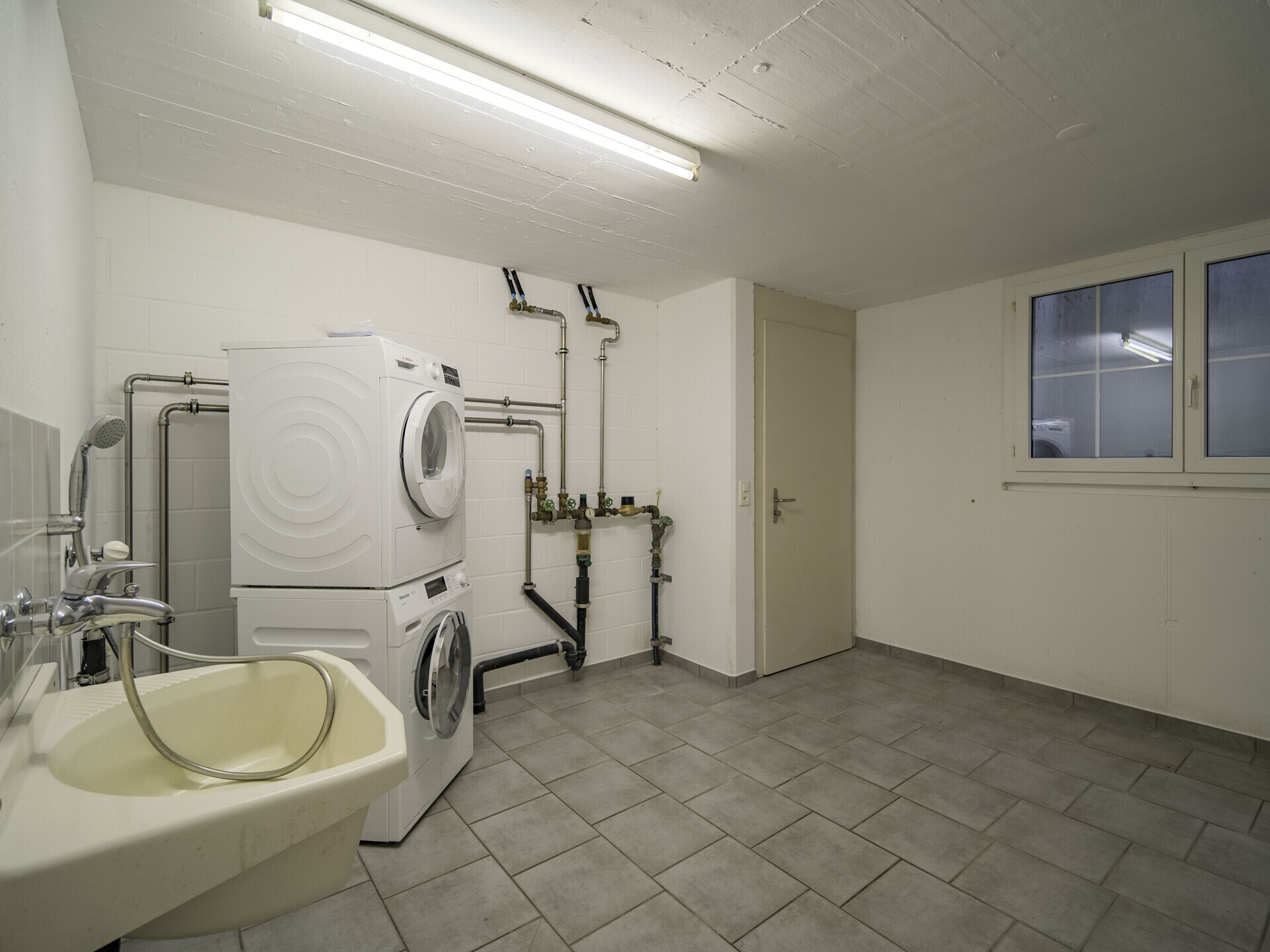 Hauswirtschaftsraum mit Waschmaschine und Waschbecken