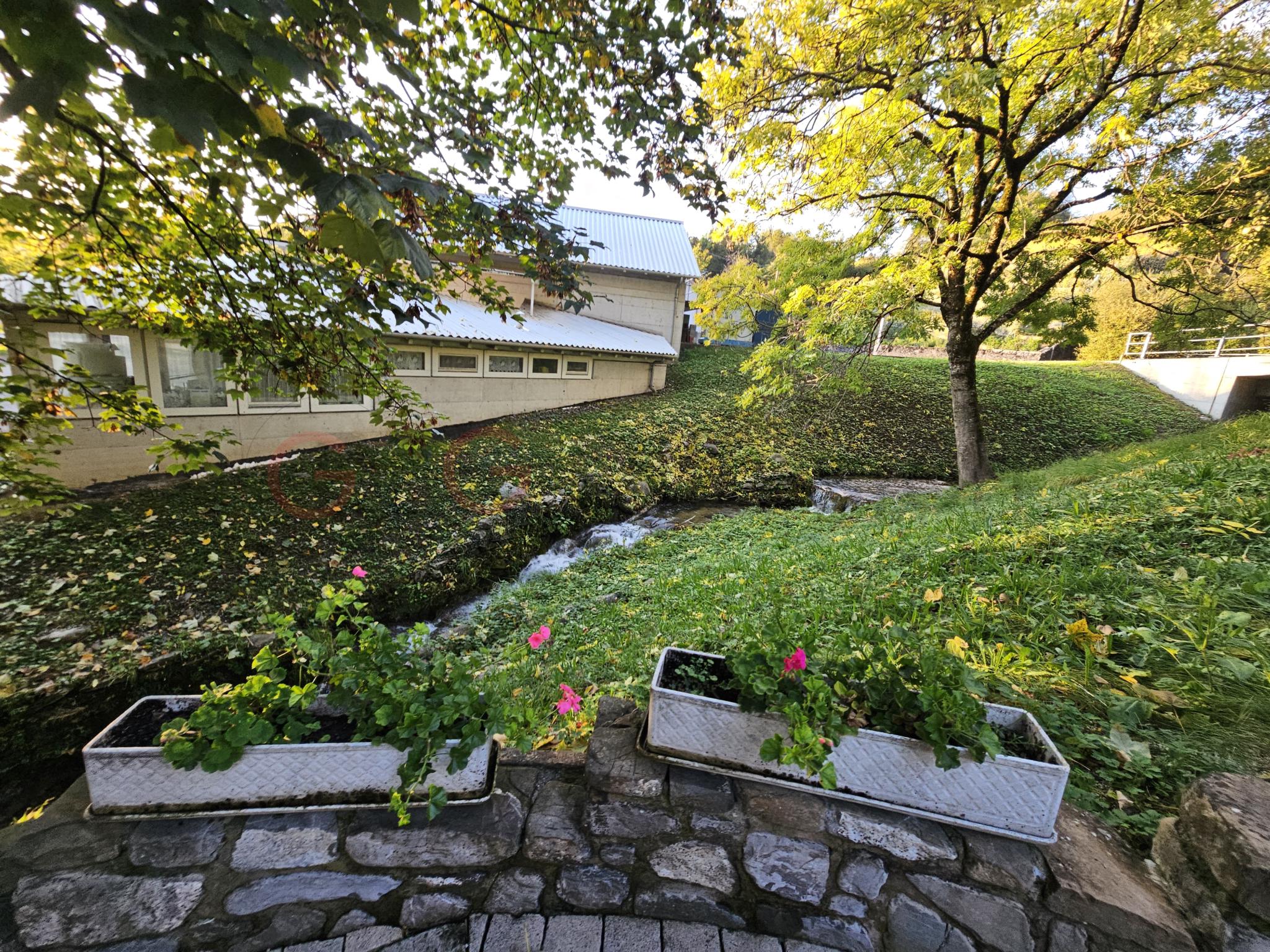 Gartenansicht mit Gebäude am Bachlauf