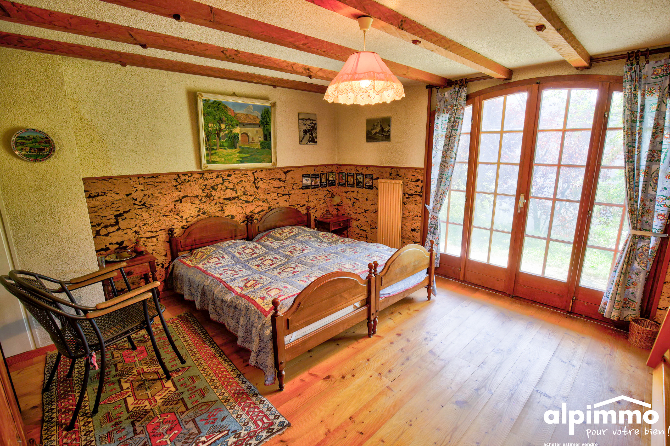 Rustikales Schlafzimmer mit Holzdecke und Balkonfenstern