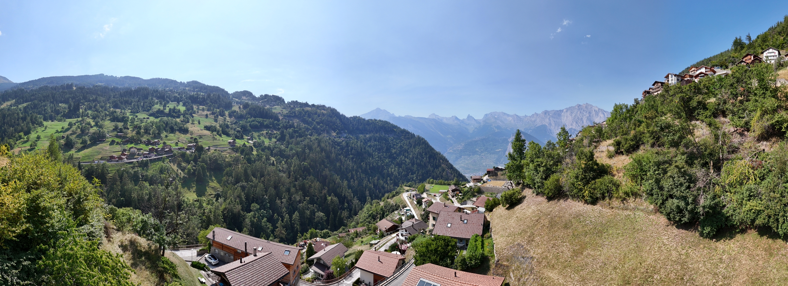 Bergtal mit alpiner Siedlung und Fernblick