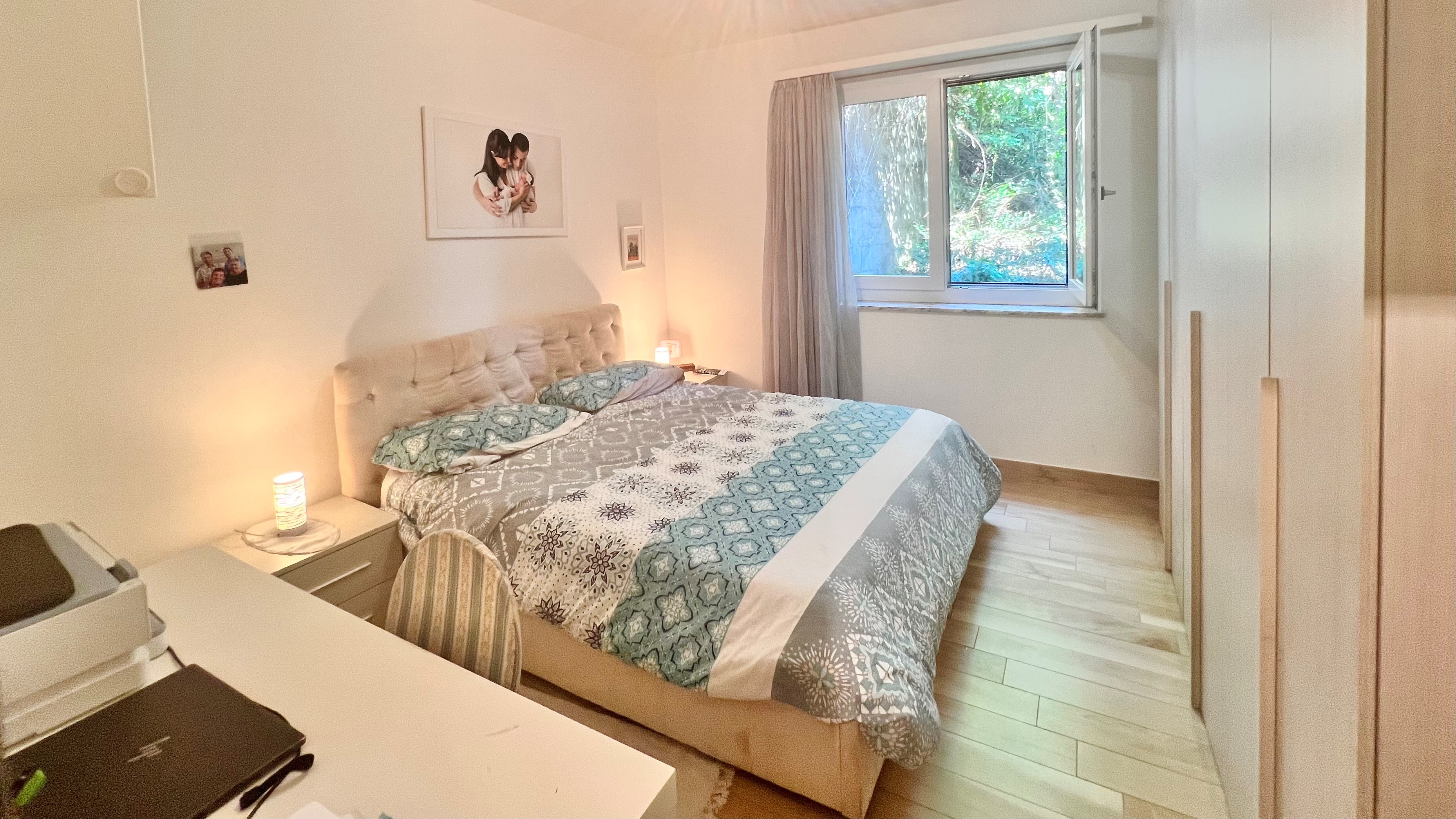 Helles Schlafzimmer mit Bett und Fensterblick ins Grüne