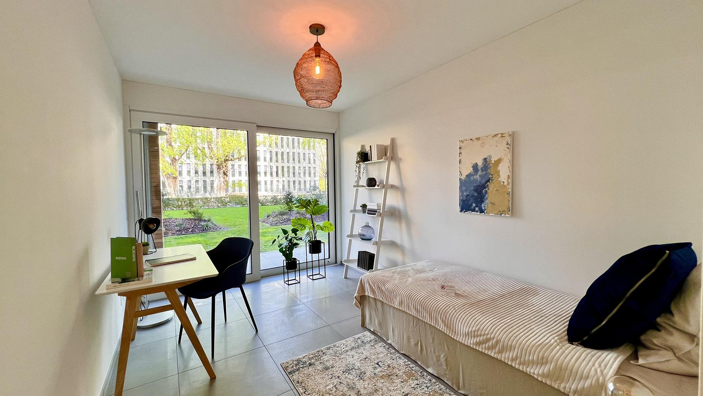 Helles Einzimmer-Zimmer mit Bett und Schreibtisch