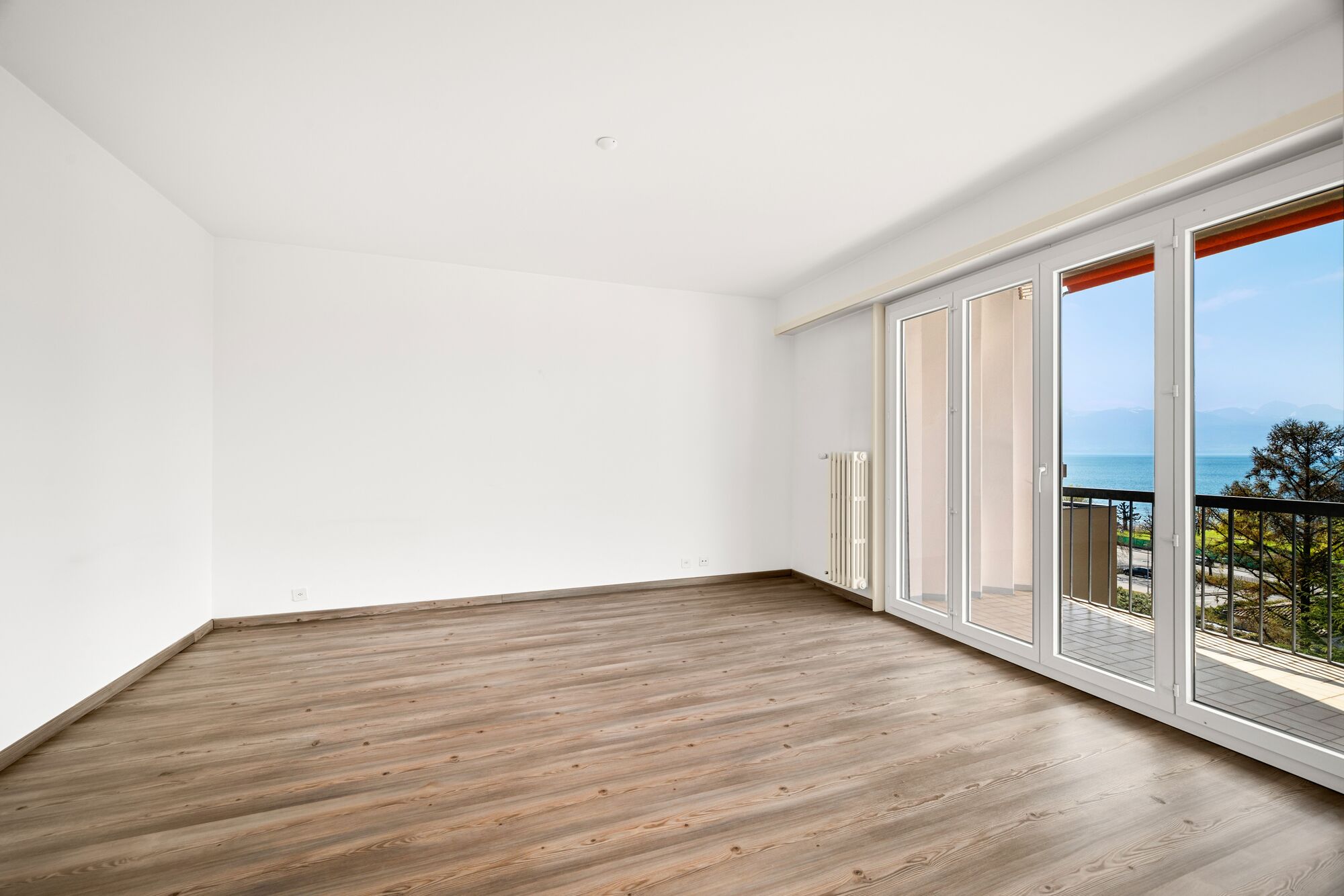 Leerer, heller Wohnraum mit Balkon und Meerblick