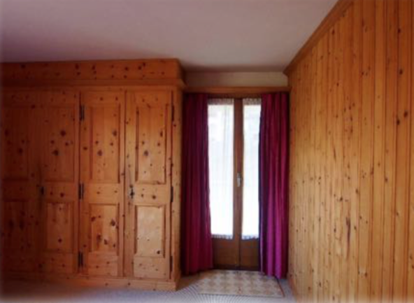 Holzvertäfeltes Zimmer mit Einbauschrank und Fenstertür