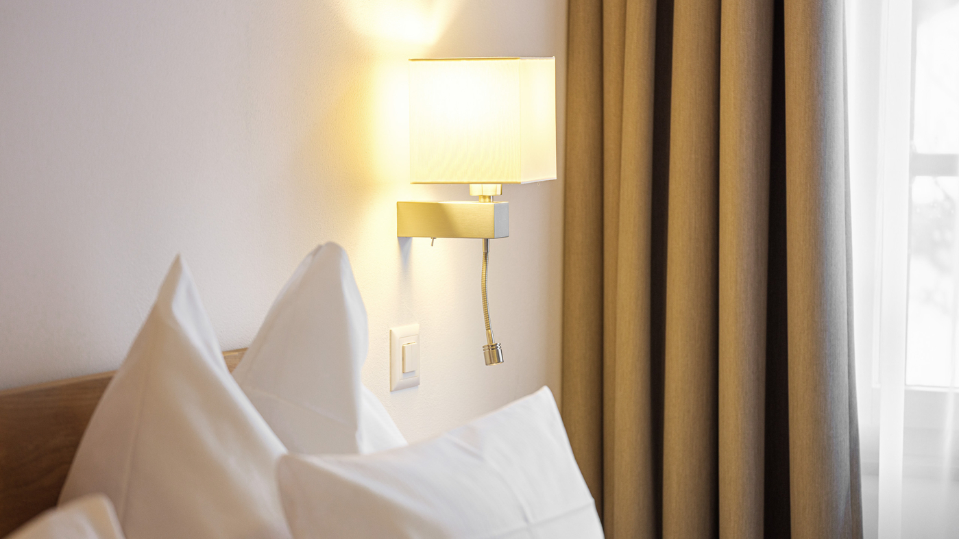 Gemütlicher Schlafzimmerausschnitt mit Bett und Wandlampe