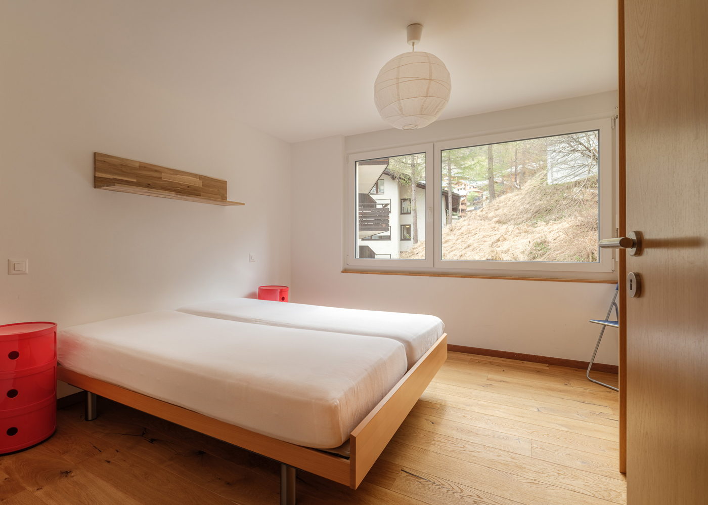 Helles Schlafzimmer mit Naturholz und Blick ins Grüne