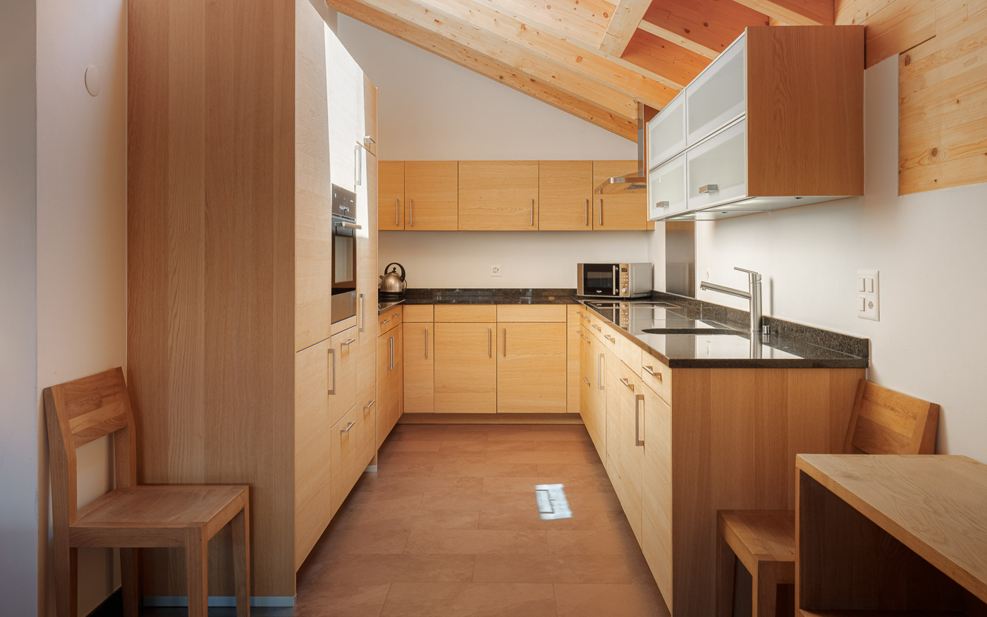 Helle Küche mit Holzfronten und sichtbarer Holzdecke