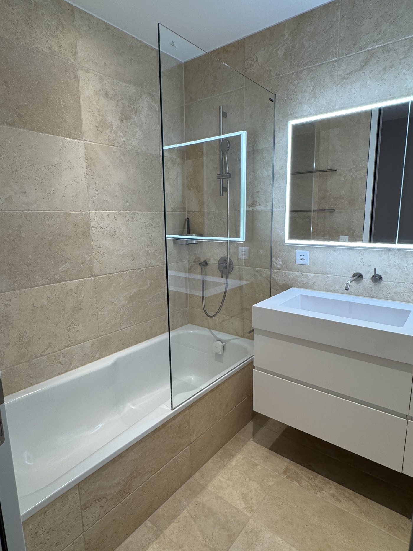 Modernes Badezimmer mit Badewanne und beleuchtetem Spiegel