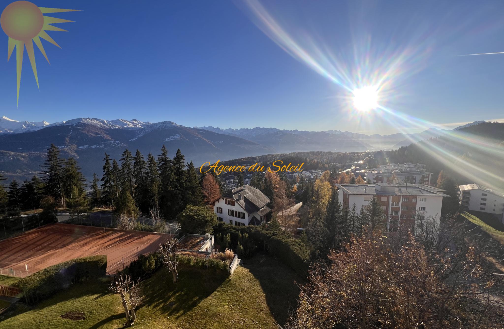 Alpenpanorama mit Siedlung und Sonne
