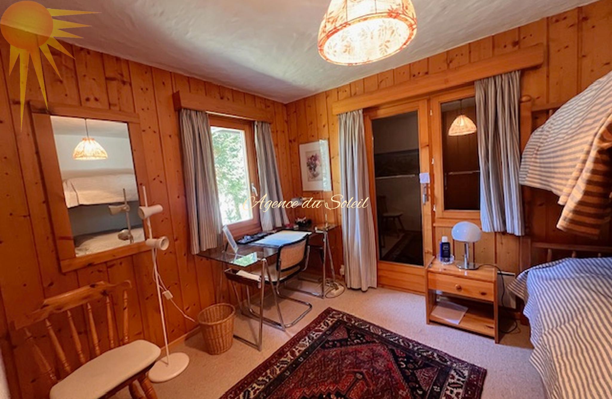 Gemütliches Holzschlafzimmer mit Schreibtisch und Balkonzugang